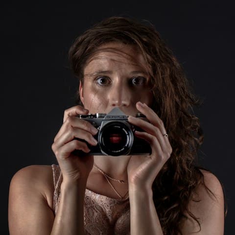 Porträt einer Fotografin mit Kamera vor der Brust